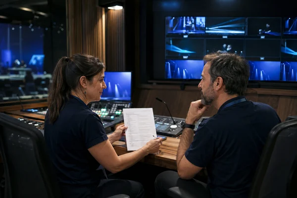 Dos operadores realizan el relevo en el puesto de control audiovisual.