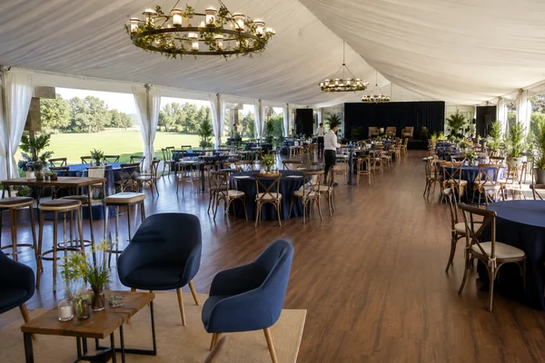 Interior de una carpa preparada para un encuentro empresarial con piso y mobiliario.